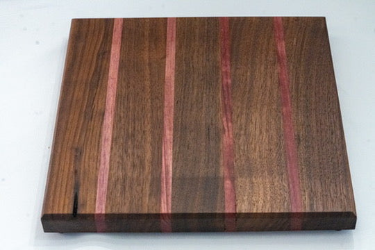 his cutting board features a walnut wood base, accented by four stripes of alternating Padauk (red) wood. The captivating hues you behold are the authentic colors of each wood, untouched by any stains or dyes.