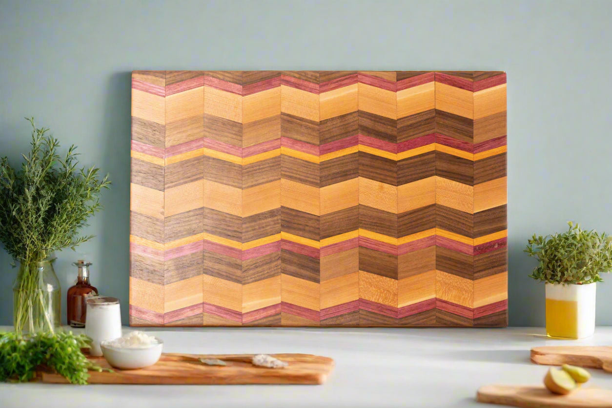 Introducing our handcrafted Chevron cutting board, a stunning addition to your kitchen. Made from Paduak, Walnut, Mahogany and Yellow Heart wood, this spacious and sturdy board is not only unique, but also expertly crafted for an elegant touch. Elevate your cooking experience with this timeless piece.